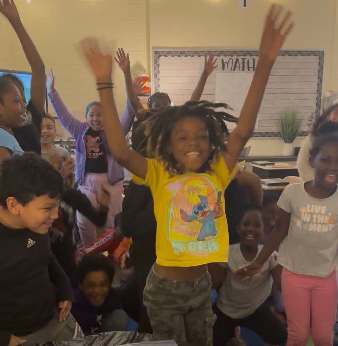 Excited students celebrating with hands raised in classroom setting